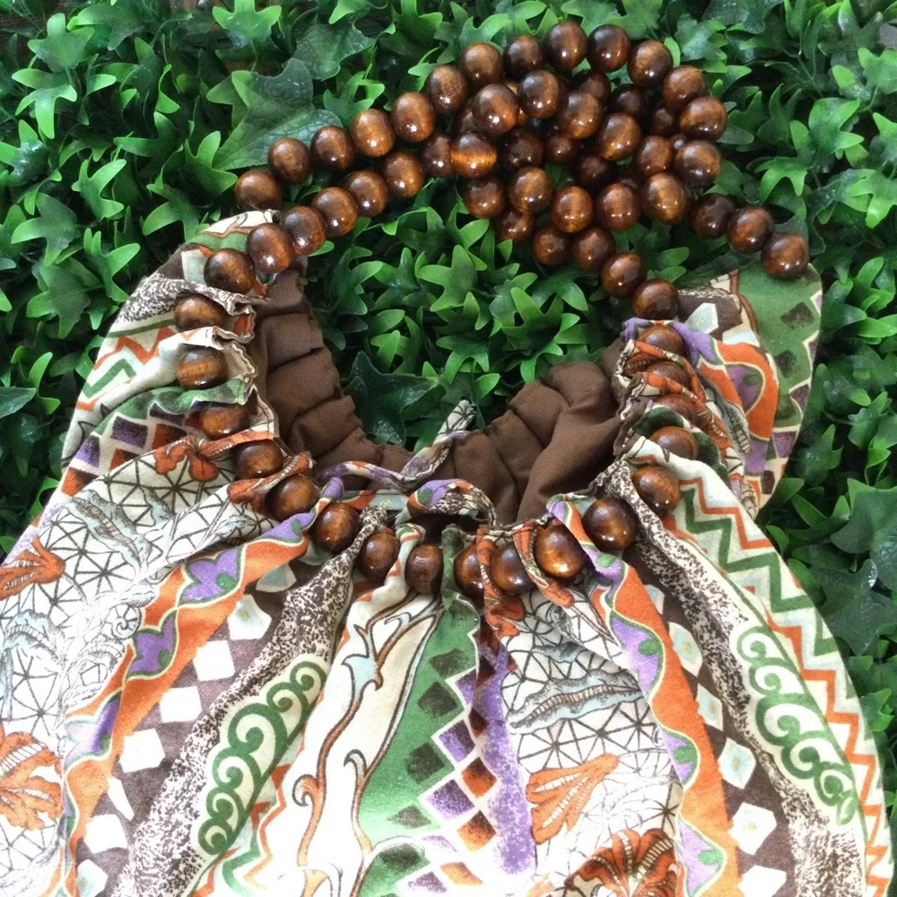 Reversible hobo tote with brown wood balls straps. Has a tie strap closu…
